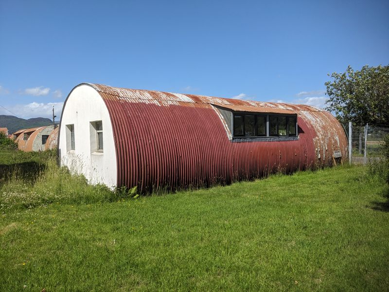 Nissen hut with peeling paint and rusting corrugated sheets