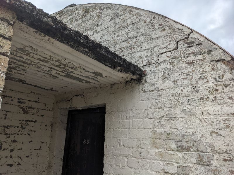 Hut 83 exterior showing cracking gable end and peeling paint